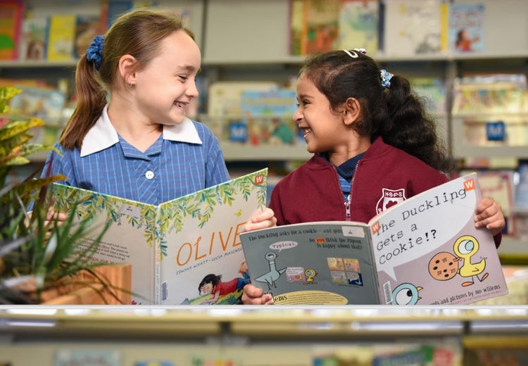 Two girls reading a book in the library