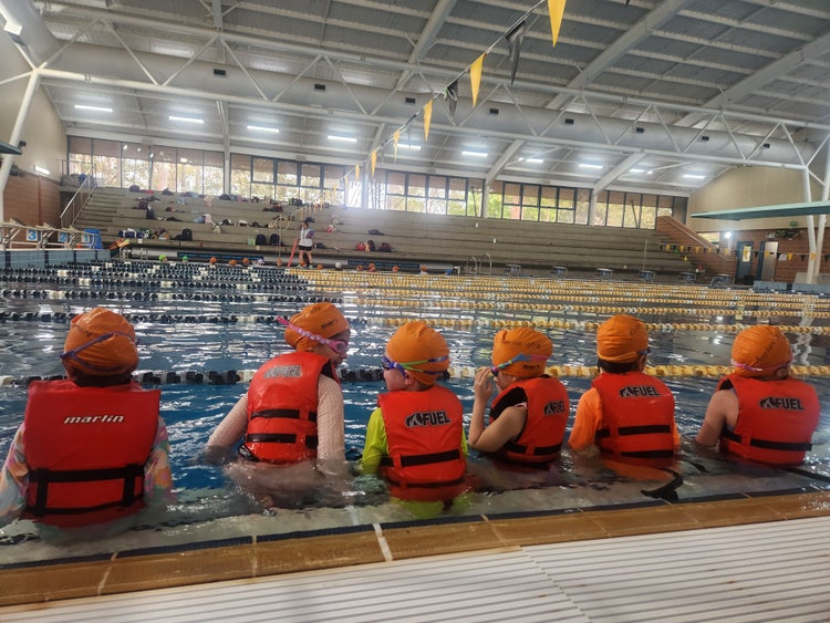 Six children sitting by the pool for their swimming lesson
