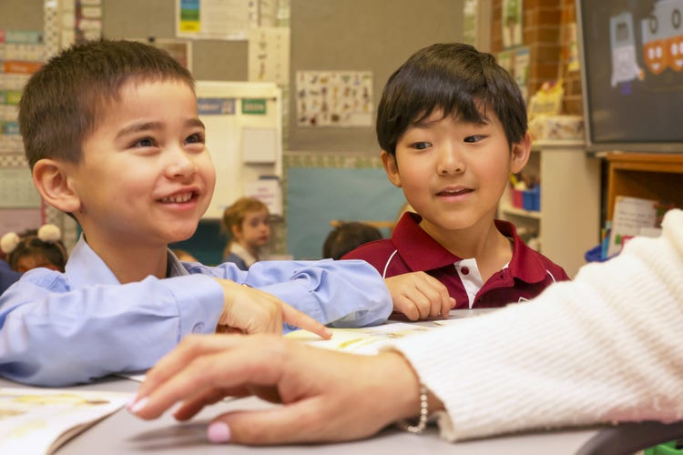 Students working with their teacher at a desk